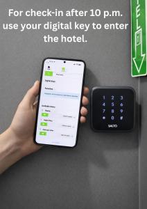 una mano che tiene un iPhone accanto a un telecomando di Hotel Bayer's a Monaco