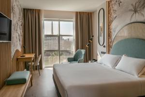 a hotel room with a bed and a desk and a window at Vincci Maritimo in Barcelona