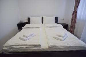 a bed with white sheets and folded towels on it at Süni Vendégház in Căpîlniţa