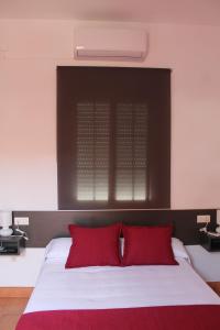 a bedroom with a bed with red pillows and a window at Hostal Rte. Casa Miguel in Matalascañas