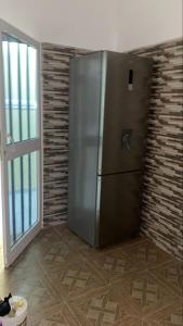 a stainless steel refrigerator in a room with a brick wall at villa Eden in Vougomé