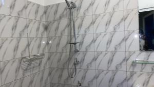 a shower in a bathroom with a white marble wall at villa Eden in Vougomé