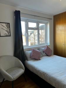 a bedroom with a bed and a chair and a window at Urban Snooze in Herne Hill