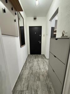 a hallway with a black door and wooden floor at Cozy green apartament in Mediaş +10 photos