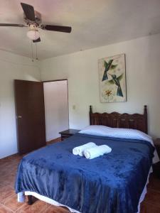 a bedroom with a bed with a blue blanket and a fan at Casa El Limón in Yelapa