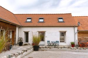 a white house with two blue chairs in the courtyard at Les Bobos à la ferme in La Madelaine-sous-Montreuil