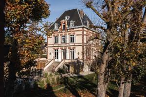 an old house with a black roof and trees at Villa Chantereine in Cabourg