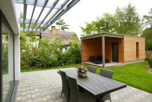 a patio with a wooden table and chairs and a house at "Strandhus Finka" in Dierhagen