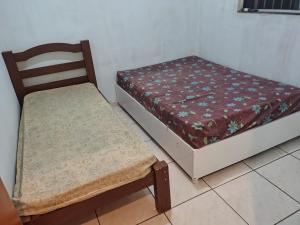 two beds and a chair in a room at Casa temporada soares in São José da Barra