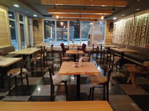 a restaurant with wooden tables and chairs and windows at Etno kuca Brzece in Brzeće