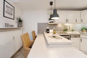 a kitchen with white cabinets and a table with a bottle of wine at Haus Strandgeflüster Sandbank in Grömitz