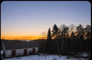 a house in the snow with the sunset in the background at Little Sven#s House in Mellansel