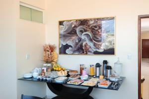 a table with food and a painting on the wall at Pousada Carnaúbas - Sobral in Sobral