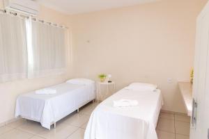 two beds in a white room with a window at Pousada Carnaúbas - Sobral in Sobral +17 photos