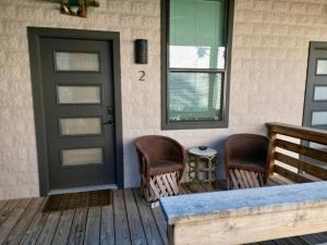 a front porch with a door and two chairs at Lodge 2 on the Mason TX square in Mason