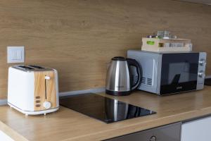 a kitchen counter with a coffee maker and a microwave at Hotel Cheese in Shumen