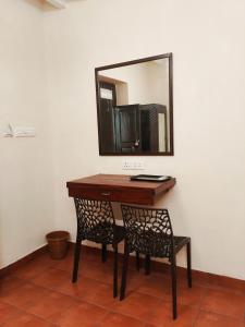 a mirror on a wall with a table and a chair at La Maison D'Ellappa in Pondicherry
