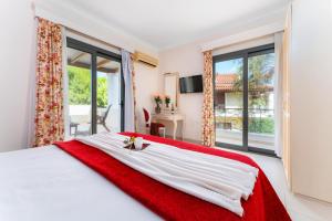 a bedroom with a large white bed with a red blanket at Ionian Coco Palm Beach Villas in Tsilivi +101 photos