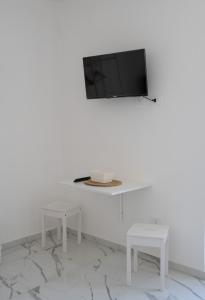 a white room with two tables and a tv on a wall at Renna's in Grammichele