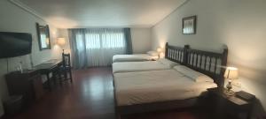 a hotel room with two beds and a desk and a television at Hotel Conde Rodrigo II by eme hoteles in Ciudad-Rodrigo