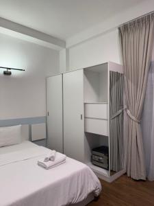 a white bedroom with a bed and a cabinet at MAIAM Homestay in Ho Chi Minh City