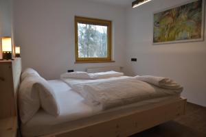 a bed with white sheets and a window in a room at Das DolomitenNest in Dölsach
