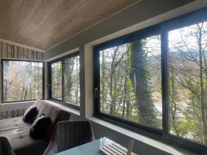 a living room with a couch and three large windows at La Noirie in Saint-Étienne