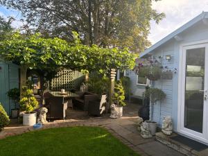 a backyard with a table and chairs under a tree at Weston's Wood Cabins in Blakeney