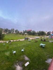 a park with tables and chairs in a field at Kehkashan in Shongran