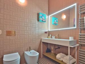 ein Badezimmer mit Waschbecken, Toilette und Spiegel in der Unterkunft Homeby, Cinisca Suites in Bologna