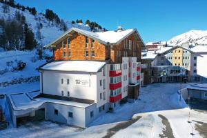 a building with snow on the roof in a city at Hotel Enzian - Adults Only in Obertauern