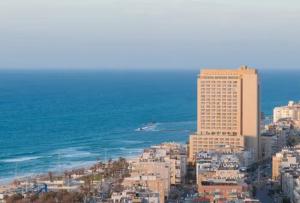 a city with a tall building next to the ocean at חדר על הים בבת ים in Bat Yam