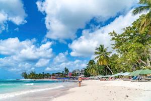 a person walking on a beach with palm trees at 108 Sapphire Beach Condos Barbados in Christ Church