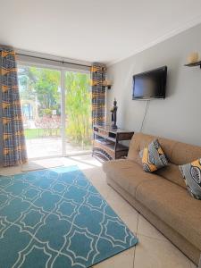 a living room with a couch and a flat screen tv at 108 Sapphire Beach Condos Barbados in Christ Church
