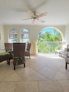 a living room with a ceiling fan and a table and chairs at 108 Sapphire Beach Condos Barbados in Christ Church