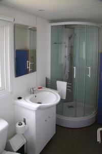 uma casa de banho com um lavatório e uma cabina de duche em vidro. em Parque de Campismo Orbitur Canidelo em Vila Nova de Gaia