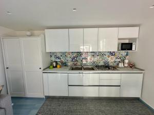 a kitchen with white cabinets and a sink at Dimora Rosella in Tramonti