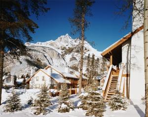 a house in the snow with a mountain in the background at Banff Rocky Mountain Resort in Banff