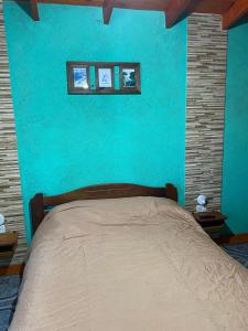 a blue bedroom with a bed with three pictures on the wall at Departamento El Delfín in Tanti