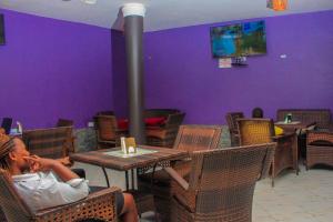 a woman sitting at a table in a restaurant at Moto-Moto Cottages in Mbarara