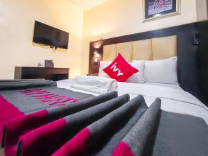 a hotel room with a large bed with pink pillows at Aotel Hotels & Suites - Ojota in Lagos