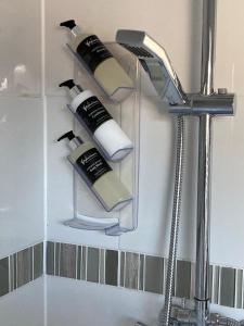 a shelf with four bottles of hair products on a wall at Skyefall Apartment in Uig +21 photos