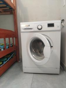 a white washing machine in a room next to a bed at Cozy apartment close to everything in Asunción