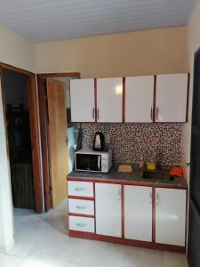 a kitchen with white cabinets and a microwave at Cozy apartment close to everything in Asunción