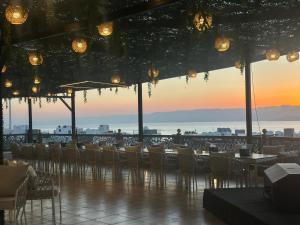 a restaurant with tables and chairs with a sunset in the background at Grand Season Hotel in Aqaba