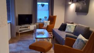 a living room with a couch and chairs and a tv at Lüttje Warfthuus in Krummhörn