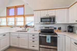 a kitchen with white cabinets and a stove top oven at On Island Time - KDH MP 7, 275 Yds to Beach, Pool, Hot Tub, Pool Table, Flex Stays in Kill Devil Hills
