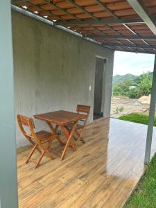 a wooden table and two chairs on a patio at Chalé Face de Cristo in Caparaó Velho