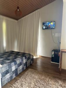 a bedroom with a bed and a television on the wall at Chalé Face de Cristo in Caparaó Velho