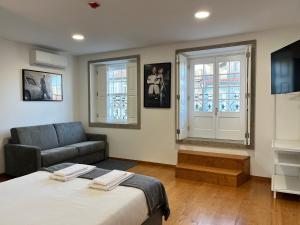 a bedroom with a bed and a couch and windows at Clérigos Cinema Guesthouse in Porto